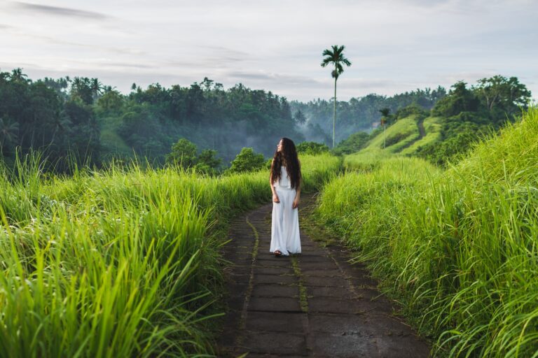 Young beautiful woman walking on Campuhan Ridge way of artists, in Bali, Ubud. Beautiful calm sunny morning